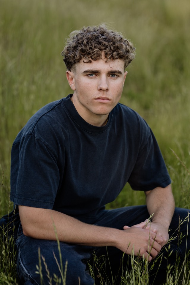 Senior seated in long grass, looking straight to camera