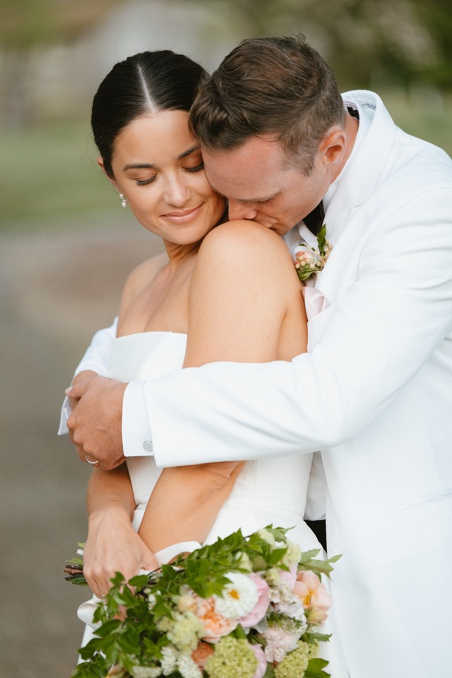 Couple embracing, groom's head resting on her shoulder
