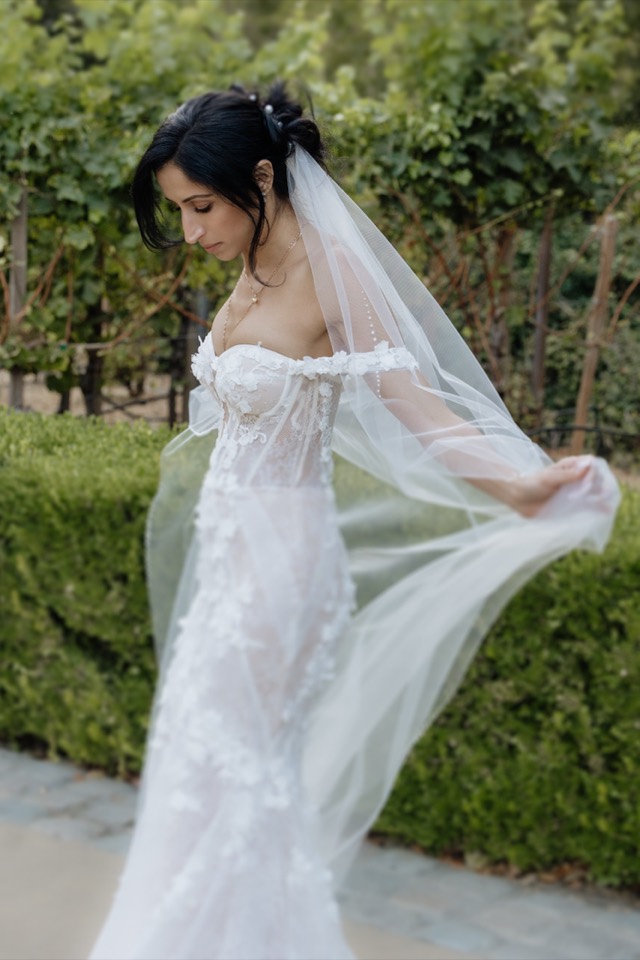 Bride turning, veil catching the light in a garden