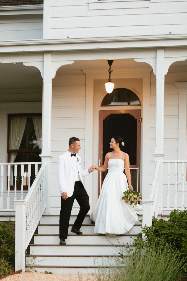 Couple on the steps of a white farmhouse venue